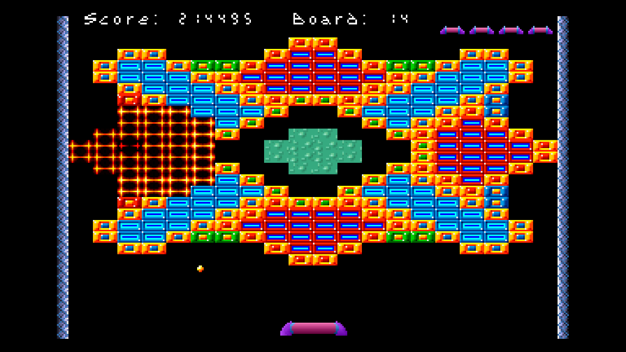 Classic, board 14 of MB40: the original pixel art mid-explosion, a glowing red and yellow grid where the left cross of exploding bricks is burning, beside red, cyan and gold bricks around a green center, with the ball below.